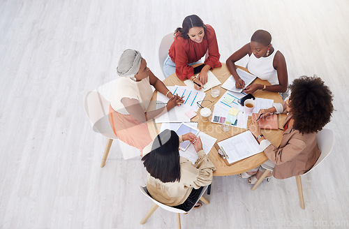 Image of Collaboration, planning and overhead with a business women team reading documents during an office meeting. Teamwork, strategy and diversity with a female employee group working together from above