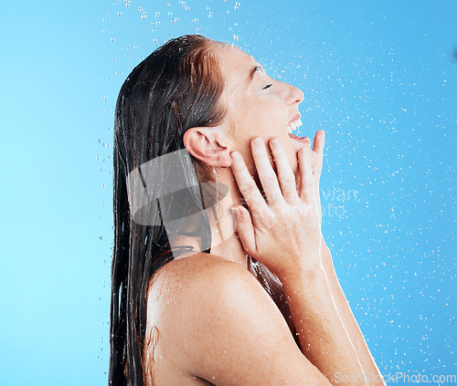 Image of Shower, water and excited smile of woman in studio, blue background and cleaning for hygiene. Happy female model washing with wet drops for beauty, skincare and grooming for morning wellness routine