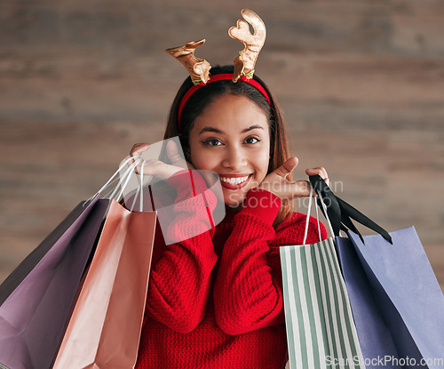 Image of Bags, portrait and woman with a reindeer headband for a festive, xmas holiday celebration. Happy, smile and face of a female model shopping for gifts or presents with christmas accessories for event.