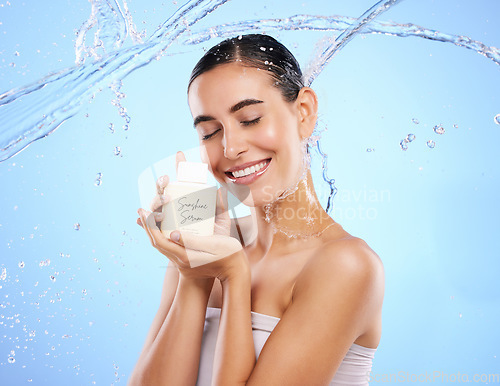 Image of Happy woman, water splash and face with skincare moisturizer, product or cream against blue studio background. Calm female with smile holding lotion or creme for beauty cosmetics or facial treatment