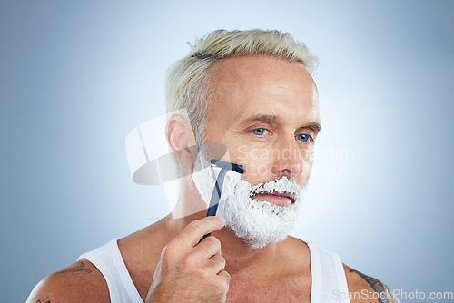 Image of Senior man, razor and shaving cream for beard grooming, skincare or hair removal against a studio background. Mature male face with shaver, creme or foam product for clean hygiene or facial treatment
