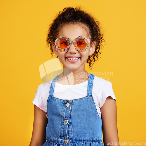 Image of Girl child, happy and sunglasses in studio portrait with smile, summer style and yellow background. Mixed race model, female kid and fashion frame on face with kids clothes, aesthetic and lifestyle