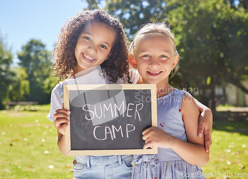 Image of Summer camp, portrait or girls hugging in park together for fun bonding, development or playing in outdoors. Happy young best friends smiling or embracing on school holidays outside with board sign