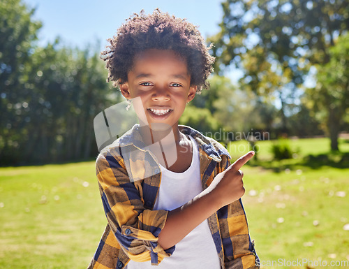 Image of African boy, pointing and park portrait with smile, happiness or playful in outdoor sunshine. Young black child, point and hand gesture on grass in summer with excited face, happy and freedom to play