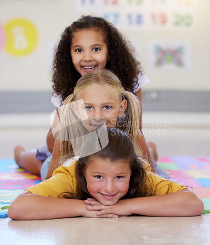 Image of School kids, lying together and pile on floor, portrait and classroom for smile, solidarity or diversity. Girl, children and class at academy, happy or multicultural friends with support for learning