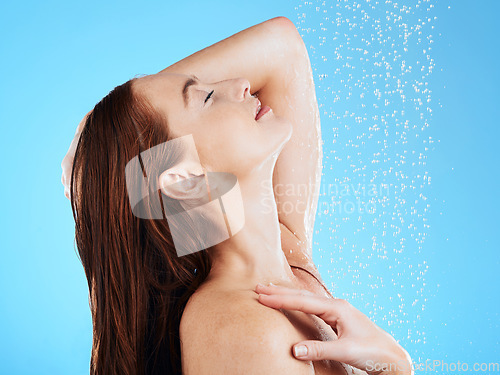 Image of Shower, water and calm woman in studio, blue background and cleaning for hygiene, wellness and fresh routine. Happy female model washing with wet drops for beauty, skincare and grooming for self care
