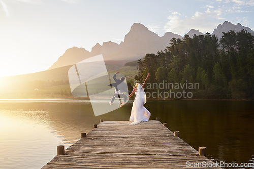 Image of Wedding, bride and groom jumping in lake together with passion, love and romance. Crazy fun, marriage and happy couple on pier to celebrate romantic, loving relationship in nature and water from back