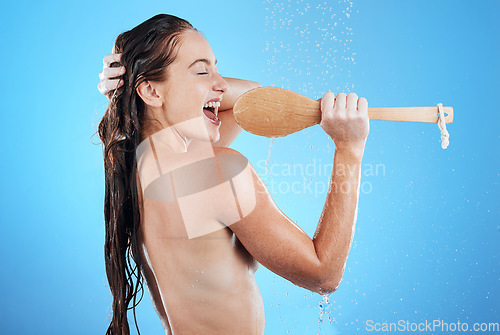 Image of Shower singing, skincare and woman with happiness karaoke in a studio. Bathroom, music and happy wet female model with isolated blue background and cleaning brush for beauty routine, wellness and fun