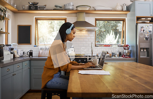 Image of Home, remote work and business woman on laptop for research project, strategy and planning in kitchen. Freelancer, focus and girl with headphones for music with documents, computer and working online