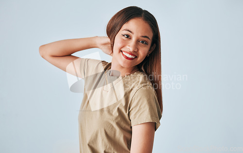 Image of Portrait, smile and a woman in studio on a gray background feeling positive, carefree or cheerful. Face, happy and freedom with an attractive young female posing in clothes for contemporary fashion