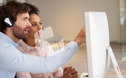 Image of Man, woman and call center coaching at computer for training, development or point at screen. Crm teamwork, tech support or learning for customer experience with diversity in office for collaboration