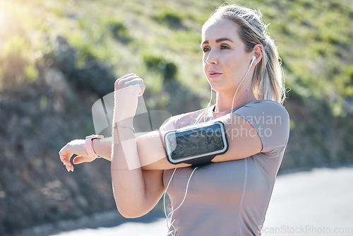 Image of Fitness, serious woman and stretching arms with music earphones for exercise, start or workout in nature. Determined and fit female in focus listening to radio in arms warm up for training outdoors