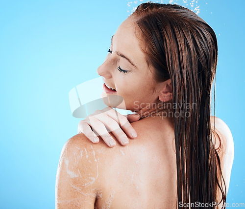 Image of Shower, beauty and back of woman with soap for wellness, body hygiene and cleaning in studio. Skincare, bathroom and happy girl with water splash, cosmetics and washing products on blue background