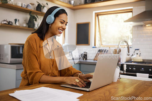 Image of Home, remote work and business woman on laptop for research project, strategy and planning in kitchen. Freelancer, smile and girl with headphones for music with documents, computer and working online