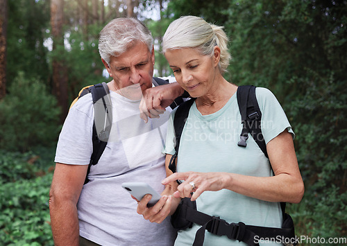 Image of Hiking, forest and elderly couple with phone for gps, location or navigation while exploring together. Online, maps and active senior man with woman checking direction while backpacking in nature