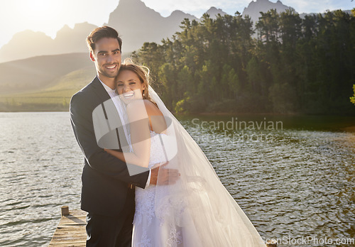 Image of Happy, hug and portrait of a married couple by a lake for a ceremony, celebration and marriage. Smile, affection and a bride and groom hugging after wedding and relationship commitment in nature