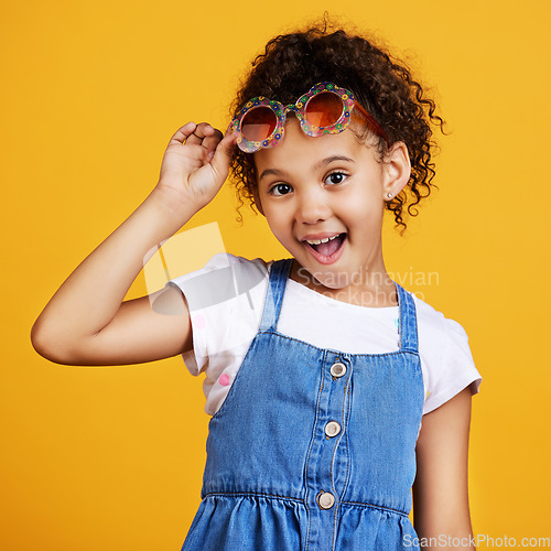 Image of Girl child, smile and sunglasses in studio portrait for summer style or happy by yellow background. Mixed race model, female kid or fashion frame on face for surprise expression, eye care and youth