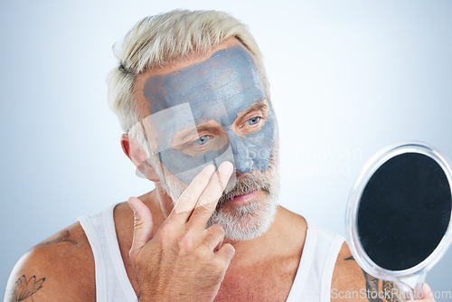 Image of Man, mirror and clay mask for face skincare, wellness and organic cleaning with smile by studio background. Elderly male, hand and natural charcoal product for facial cosmetics for dermatology detox