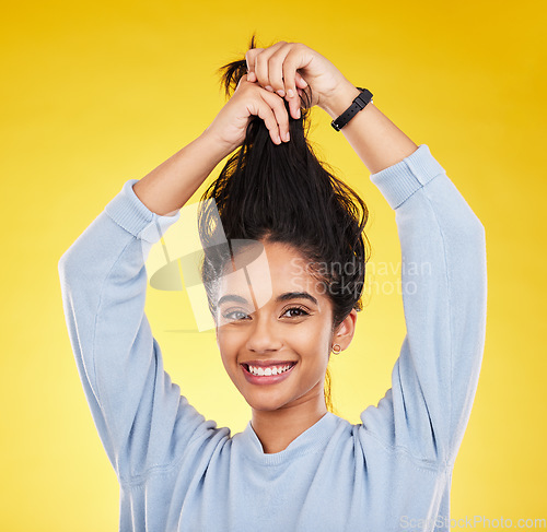 Image of Young woman, haircare and playful, smile in portrait and hair in air with gen z and fashion on yellow studio background. Happiness, youth and silly Indian female, happy with growth with shine