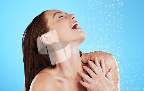 Image of Shower, water and woman laughing in studio, blue background and cleaning for hygiene. Happy female model washing with wet drops for beauty, skincare and grooming for self care, wellness and happiness