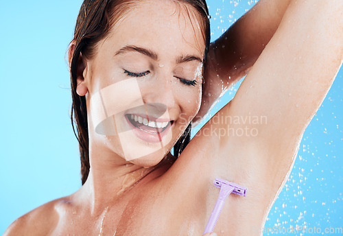 Image of Happy woman in shower, grooming and shaving armpit, hygiene and water drops with razor on blue background. Skincare, hair removal with female shaving underarms, eyes closed and smile in studio