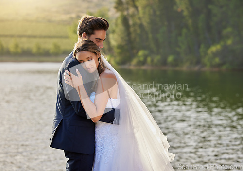 Image of Wedding couple, hug and relax by lake for love on romantic getaway or honeymoon in nature. Calm woman hugging man in happy marriage relaxing by the water together enjoying the loving embrace outdoors