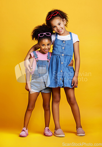 Image of Children, hug and happy portrait of sisters in studio with love, care and support on yellow background. Cute young girl kids smile together for happiness, carefree and positive attitude for family