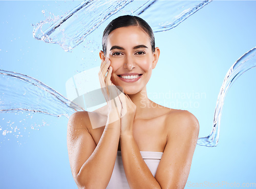 Image of Happy woman, water splash and portrait smile for skincare moisturizer, product or cream against a blue studio background. Calm female face in natural beauty cosmetics, hygiene or facial treatment