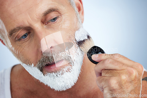 Image of Man, beard and shaving cream for grooming, skincare or hair removal against a studio background. Closeup of male face applying shave creme or foam product with brush for haircare or facial treatment