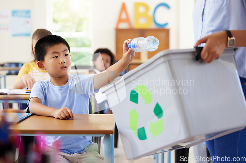 Image of Teacher, recycle bin and kid in classroom throwing trash for cleaning, climate change or eco friendly in school. Recycling plastic, sustainable learning or education with boy student in kindergarten.