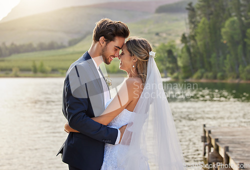 Image of Happy wedding couple, hug and love by lake for romantic honeymoon getaway in nature. Man and woman hugging touching foreheads in happiness for marriage relationship or loving embrace in the outdoors