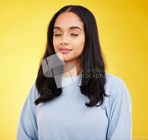 Image of Indian woman with eyes closed, meditation and zen with peace and calm isolated on yellow studio background. Mental health, wellness and balance with stress relief, young female relax with mindfulness