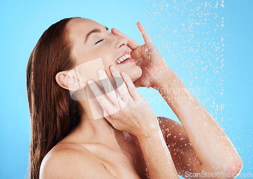 Image of Shower, water and happy woman smile in studio, blue background and cleaning for hygiene. Young female model washing with wet drops for beauty, skincare and grooming for self care, wellness or routine