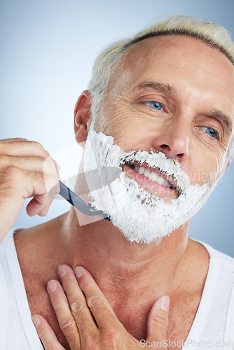 Image of Senior man, face and razor shaving beard with cream for grooming, skincare or hair removal against a studio background. Happy mature male with shaver, creme or foam for hygiene or facial treatment