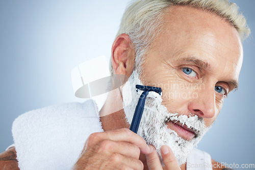 Image of Senior man, face and razor for shaving, skincare or grooming beard and hair removal against a studio background. Portrait of mature male with shaver, cream or foam cosmetics for facial treatment