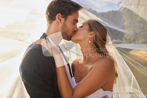 Image of Couple, wedding and kissing with vail for love, compassion or affection together in nature. Married man kiss woman on lips, hugging in marriage, relationship or loving embrace for commitment outdoors