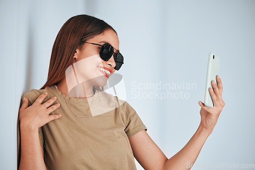 Image of Woman, wall and sunglasses in selfie with cellphone, smile and excited with fashion for summer. Girl, student and influencer with social media app, photography and profile picture with happiness