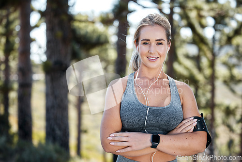 Image of Fitness woman, arms crossed and portrait smile with music for confidence in exercise, workout or training in nature. Happy, fit and confident sports female with earphones listening to radio in forest