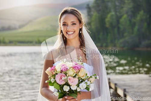Image of Portrait, happy bride and bouquet at lake, nature and celebration of commitment, union and marriage. Woman, smile and outdoor wedding of flowers, bridal fashion and excited to celebrate beautiful day