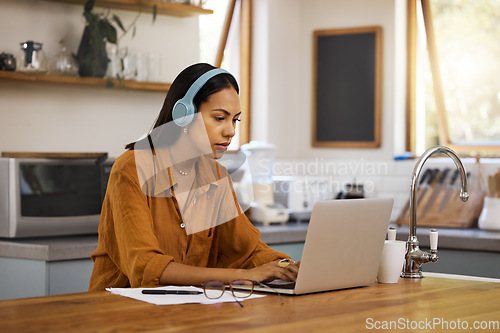 Image of Home, remote work and business woman on laptop for online project, strategy and planning in kitchen. Freelancer, computer and girl focus with headphones for music, working online and streaming audio