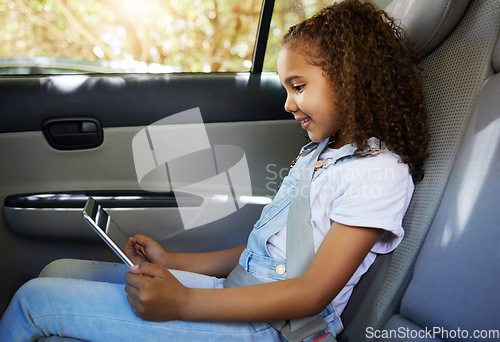 Image of Happy, road trip and a child in a car with a tablet for a movie, cartoons or video. Smile, travel and a girl sitting in a vehicle with tech, streaming online and enjoying a film for entertainment