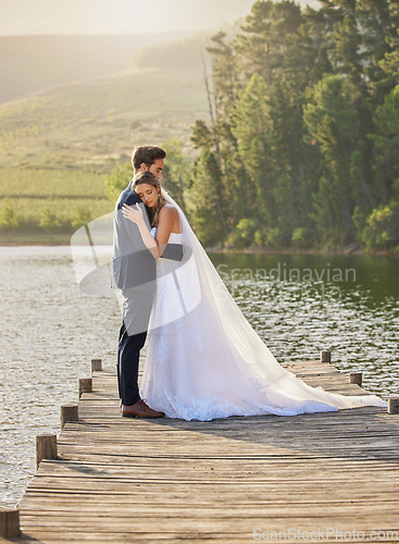 Image of Wedding couple, hug and relax by lake for honeymoon, love or romantic getaway in nature. Calm woman hugging man in happy marriage relaxing by the water together enjoying the loving embrace outdoors