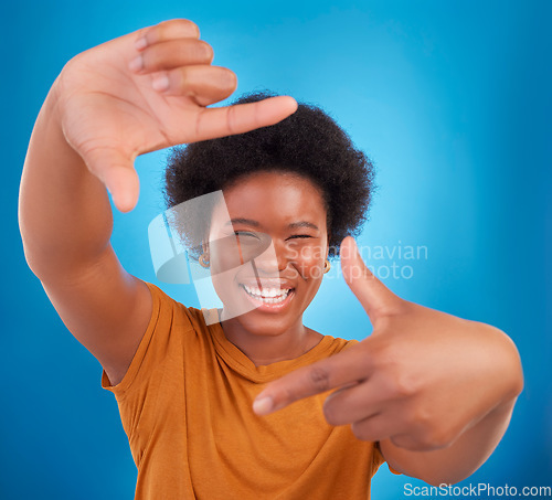 Image of Finger framing, portrait and happy black woman on blue background, studio and backdrop. Face, female and hands frame perspective, pose and smile of happiness, photography or capture profile picture