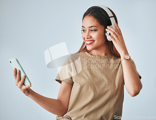 Image of Woman, music headphones and phone in studio while happy, excited and positive. Female model on white background with smartphone for internet connection or subscription listening to audio or radio