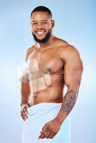 Image of Black man portrait, muscle body and towel in studio with happiness from bodybuilder fitness. Cleaning, skincare and wellness after sport workout and exercise with isolated, smile and blue background