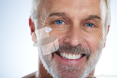 Image of Old man, cream and smile, eye and wrinkle with skincare, face and beauty, hygiene and grooming on studio background. Portrait, moisturizer and dermatology, anti aging cosmetics and male closeup