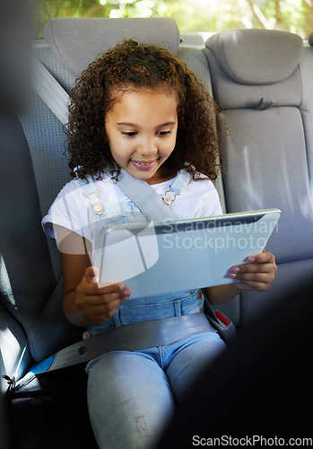 Image of Happy, watching and a child in a car with a tablet for a movie, cartoons or video. Smile, travel and a girl sitting in a vehicle with tech, streaming online and enjoying a film for entertainment