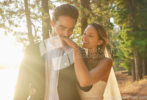 Image of Kiss, romance and couple at a nature wedding, celebration and marriage ceremony. Happy, affection and a man and woman kissing hand for loyalty, commitment and love at an event in a forest or woods