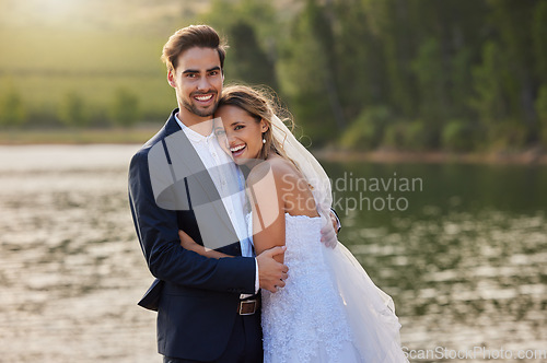 Image of Happy wedding couple, portrait and hug by lake for romantic honeymoon getaway in nature. Man and woman hugging in happiness for marriage relationship or loving embrace in commitment in the outdoors