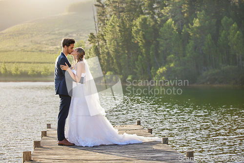Image of Wedding couple, kissing and hug by lake for love affection, intimate or romantic honeymoon getaway in nature. Man and woman kiss in happiness for marriage relationship or loving embrace outdoors